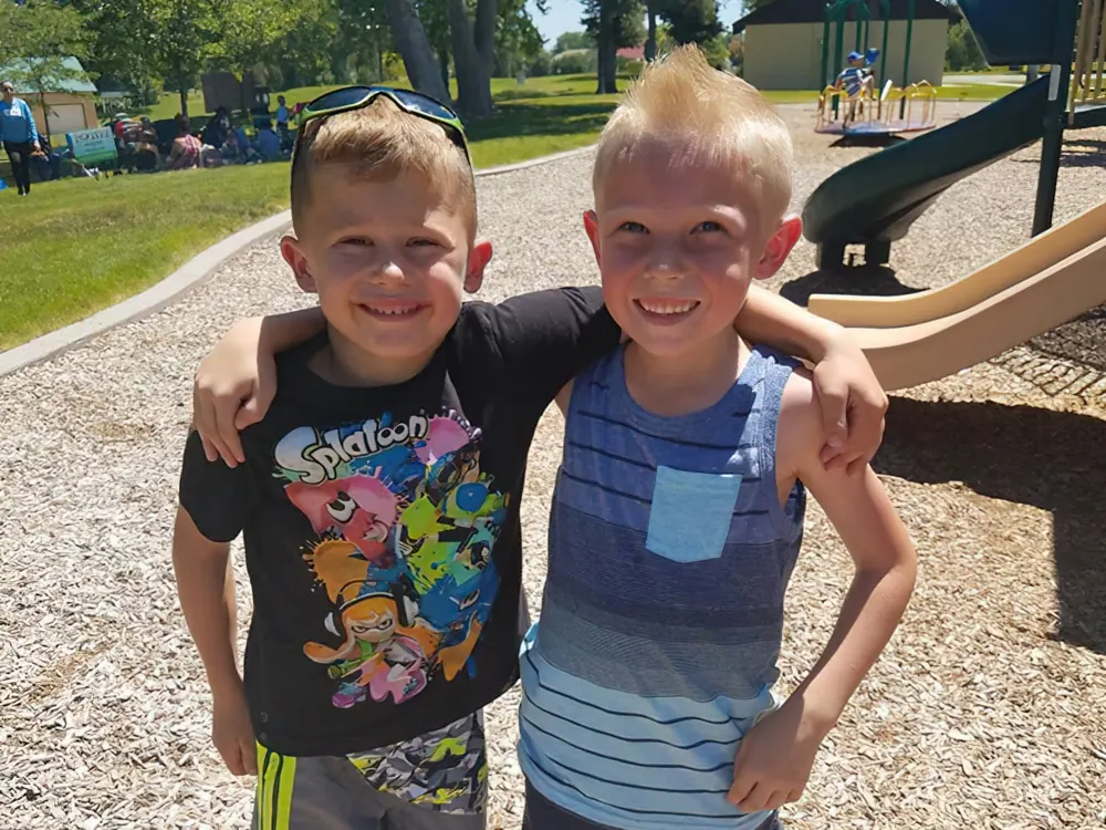 Two smiling boys with their arms around each other on a playground