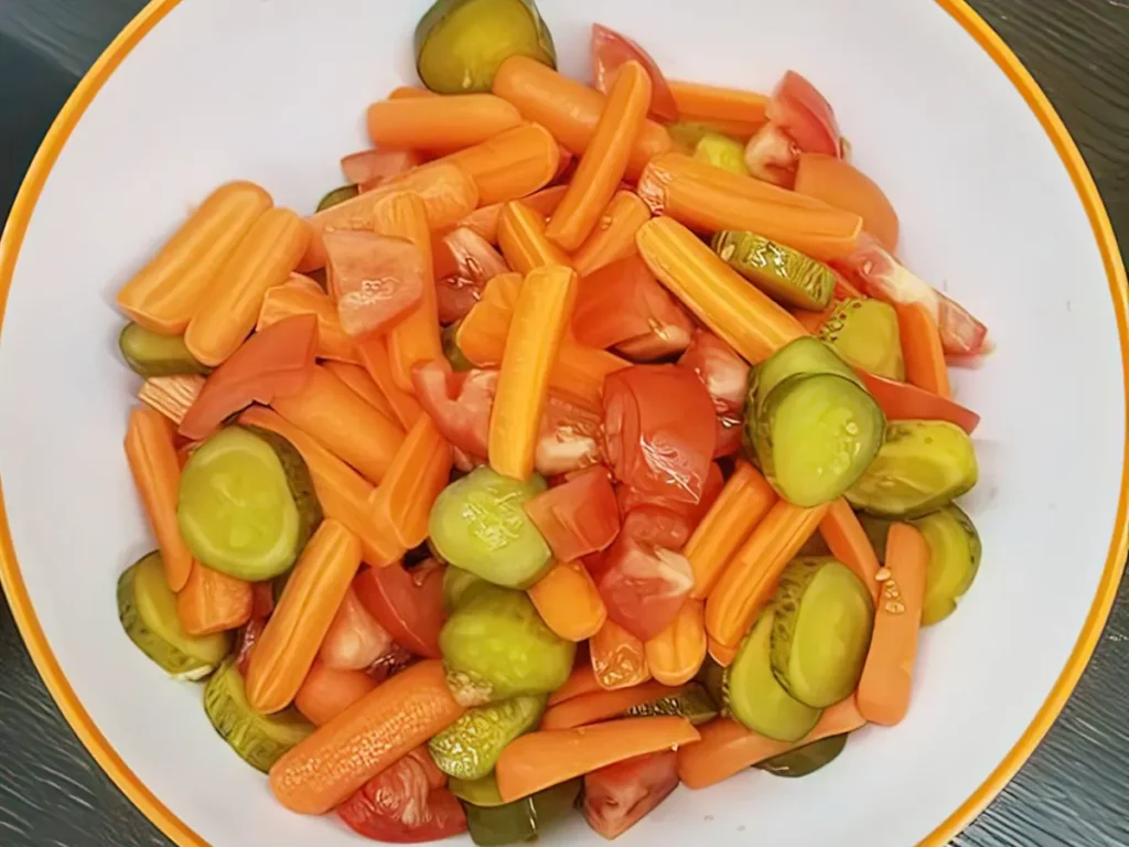 A bowl of sliced carrots, cucumbers and tomatoes