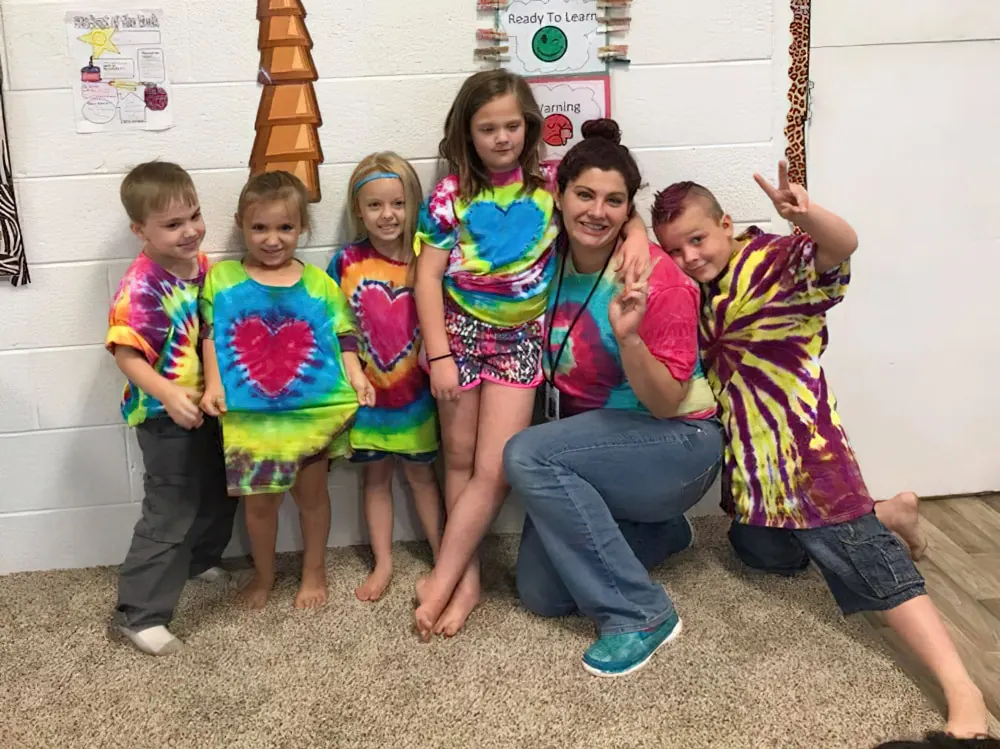 A teacher with a group of children in tie-dye T-shirts