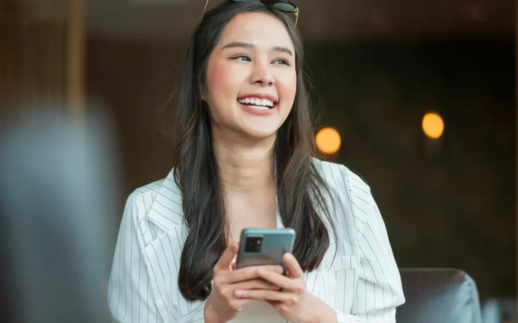 A smiling woman holding her phone
