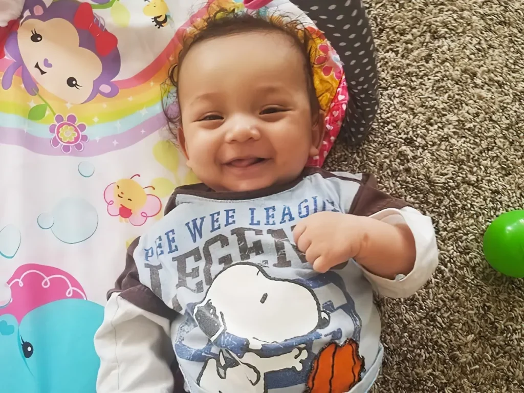 A smiling baby lying on a colorful play mat