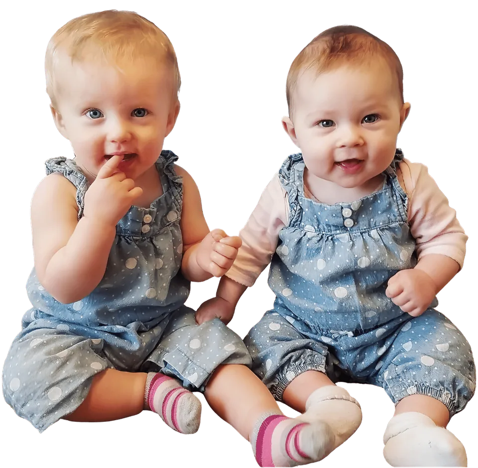 Twin baby girls in matching polka-dot denim rompers sitting side by side