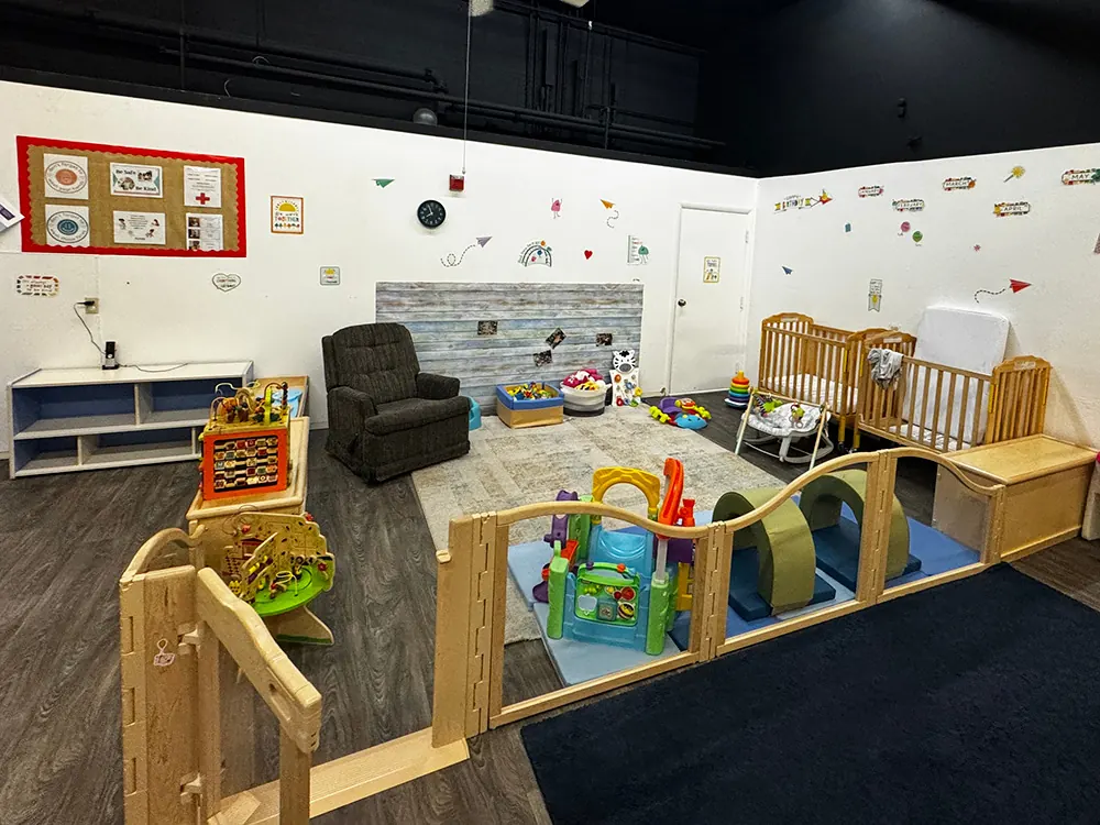 An infant room with cribs, an armchair and a wooden play yard