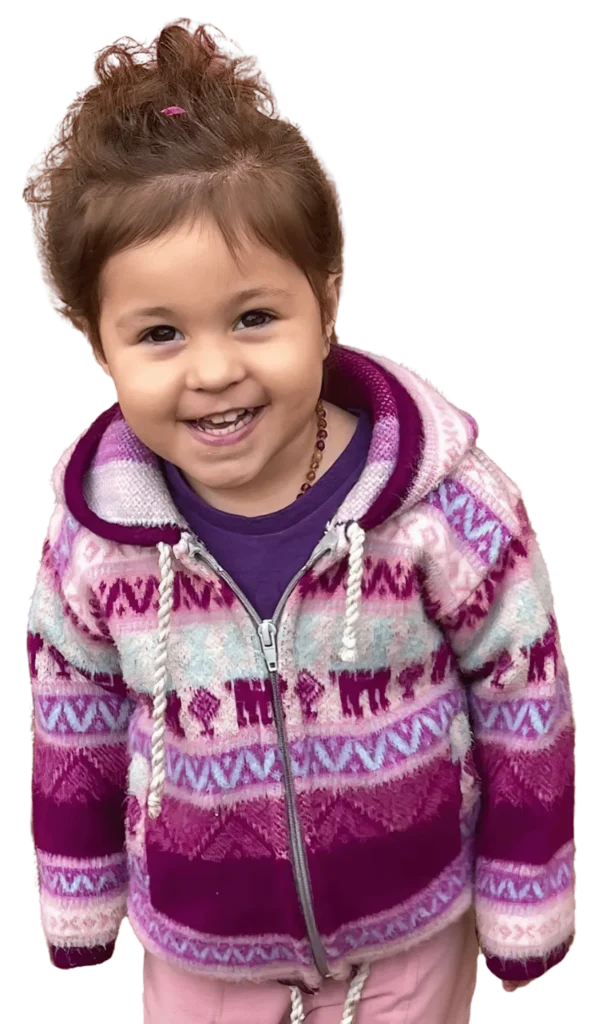A smiling little girl in a pink patterned hoodie