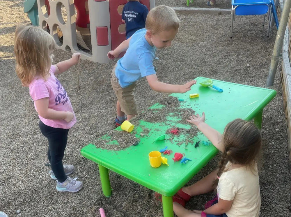 Toddlers playing at a green sand table on the playground