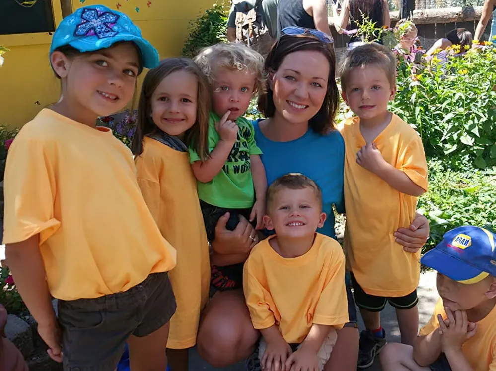 A teacher and a group of children in matching yellow T-shirts on a field trip