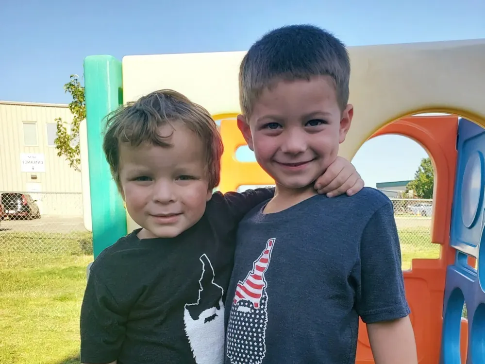 Two smiling boys with their arms around each other on a playground